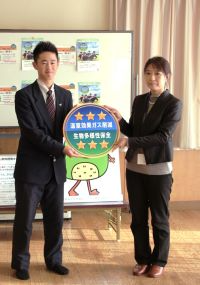 生徒代表へみえるらべるを渡す長田参事官