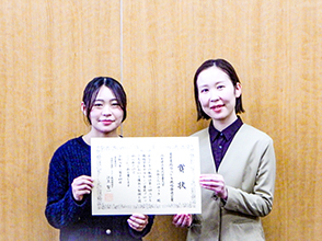 賞状を持つ須藤さん(左)と牛﨑助教(右)