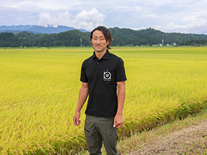 収穫間近の水稲の前で今野さん