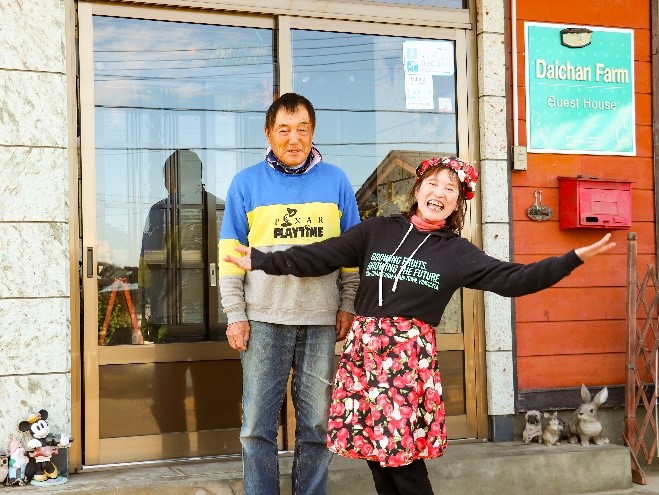 ゲストハウス玄関前で笑顔の政利さんと一枝さん