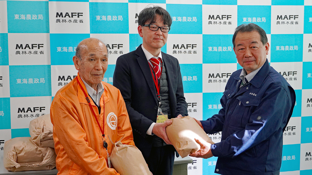 秋葉東海農政局長（右）から玄米を受け取る、セカンドハーベスト名古屋 理事長 前川 行弘氏 （左）と、 フードバンク愛知 事務局 磯野 泰治氏（中央）